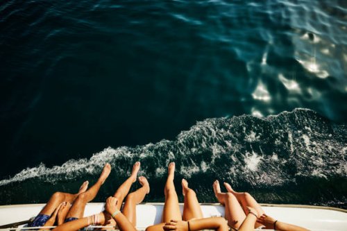 medium shot of teenagers feet hanging over side of sailboat - travel stockfoto's en -beelden