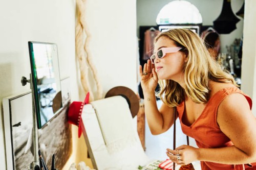 medium shot of woman trying on sunglasses while shopping during vacation - fashion stock pictures, royalty-free photos & images