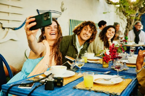 medium shot woman taking selfie of friends and family at restaurant - home decoration stock pictures, royalty-free photos & images