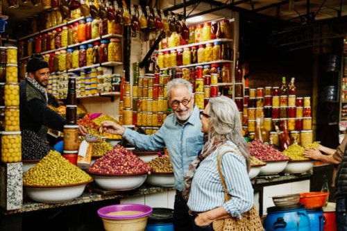 medium wide shot couple sampling olives in the medina of marrakech - travel stock pictures, royalty-free photos & images