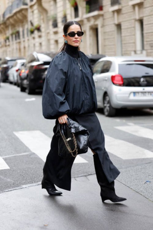 Mehrnaz Ansari wears black bomber jacket, black long skirt, black Chanel bag, black boots, black Chanel sunglasses, outside Stella McCartney, during...