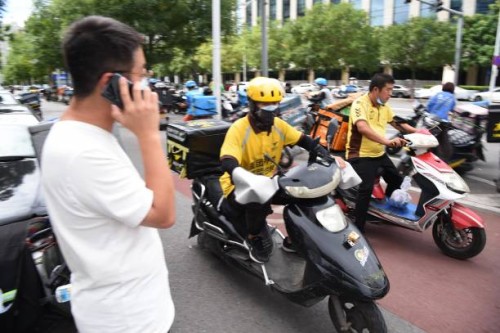 Meituan food couriers ride electric bicycles along a street on September 11, 2020 in Beijing, China.