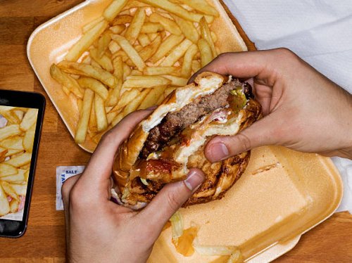 men eating hamburger and fries, phone with picture - junk food stock pictures, royalty-free photos & images