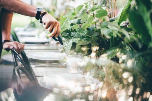 men ignite fire to decorative candles in stylish glass holders with thin wooden sticks at rustic table with elegant setting in garden closeup. - garden decoration stock pictures, royalty-free photos & images
