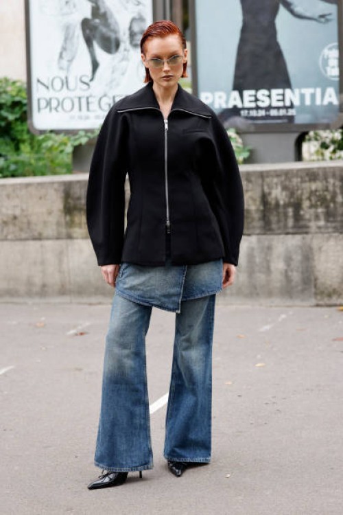 Meredith Duxbury wears black jacket, blue denim pants, black heels, outside Ganni, during Womenswear Spring/Summer 2025 as part of Paris Fashion Week...