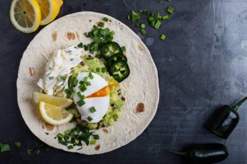 mexican style breakfast with poached egg, guacamole and coleslaw on flour tortilla - junk food stock pictures, royalty-free photos & images