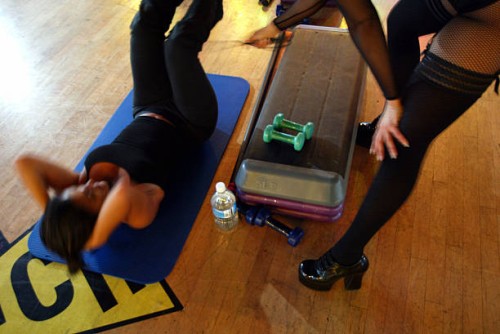 Michelle Fernandez uses her riding crop to help Myriam Fridman with her situps during an aerobics class called Whipped at Crunch October 25, 2002 in...