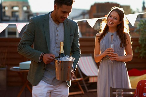 mid adult couple at party on roof terrace holding ice bucket with champagne smiling - garden decoration stock pictures, royalty-free photos & images