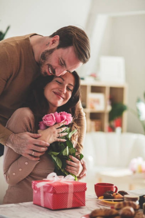mid adult man giving his girlfriend flowers and gift - home decoration stock pictures, royalty-free photos & images