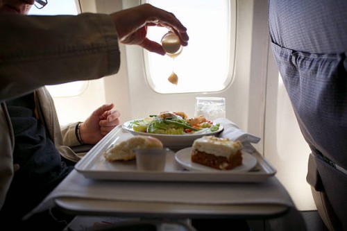 mid adult man sitting at airplane, adding mustard to salad - food stock pictures, royalty-free photos & images