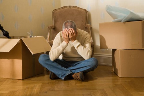 mid adult man sitting on a hardwood floor and suffering from a headache - home decoration stock pictures, royalty-free photos & images