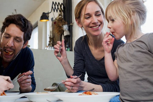 mid adult parents and two daughters eating a spaghetti meal - food stock pictures, royalty-free photos & images