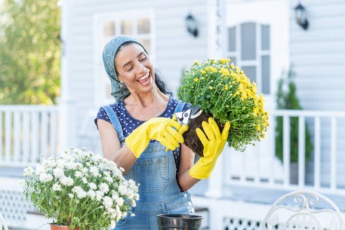 mid adult woman pflanzt blumen vor einer veranda - garden decoration stock-fotos und bilder