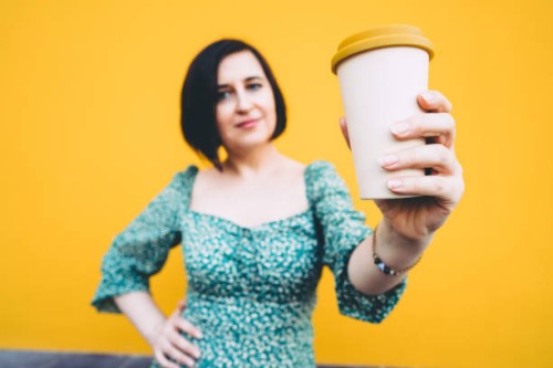 middle-aged woman with bamboo coffee cup on yellow background - junk food stock pictures, royalty-free photos & images