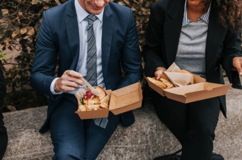 midsection of male and female business professionals having lunch while sitting on bench - junk food stock pictures, royalty-free photos & images