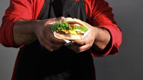 midsection of man holding burger against wall,mexicali,mexico - junk food stock pictures, royalty-free photos & images