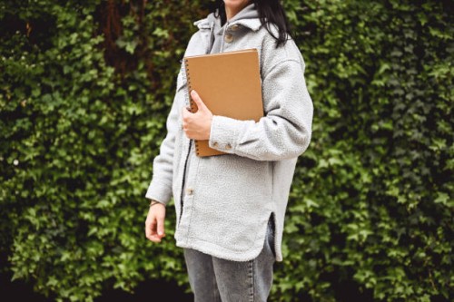 midsection of unrecognizable woman in a coat with a black note pad. - garden decoration stock pictures, royalty-free photos & images