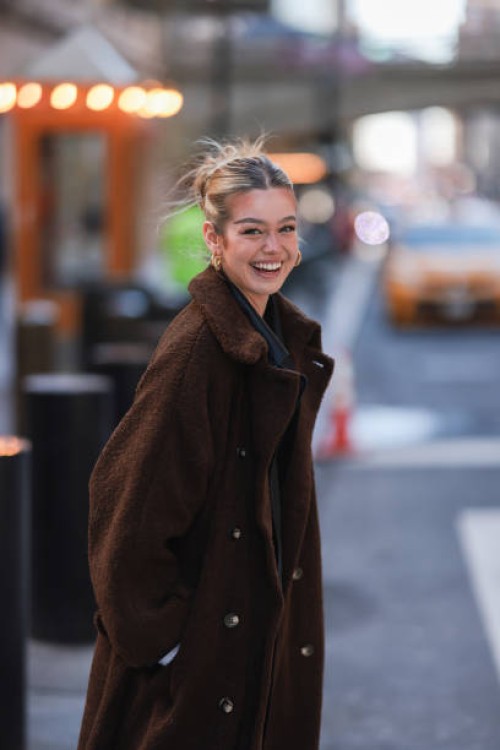 Millane Friesen is wearing a blue denim jeans, a grey hoodie and a brown long coat during New Yorker Fashion Week on February 15, 2022 in New York...