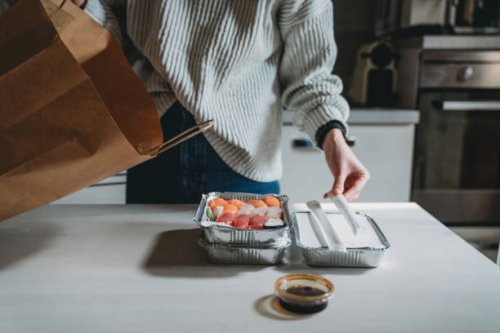 millennial woman is unpacking sushi takeaway food delivery at home - junk food stock pictures, royalty-free photos & images