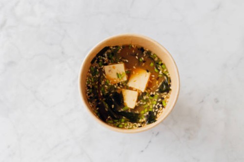 miso traditional japanese soup with tofu, mushrooms, spring onion and sesame seed mix in cardboard reusable glass. high angle view. - junk food stock pictures, royalty-free photos & images