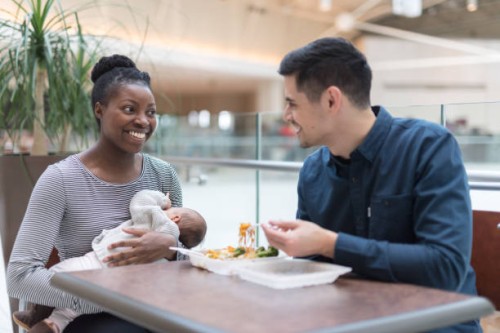 mixed race couple eating lunch with their newborn at the mall - junk food stock pictures, royalty-free photos & images