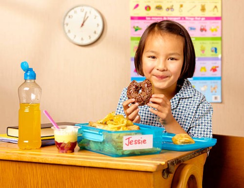 mixed race school girl eating donut - junk food stock pictures, royalty-free photos & images