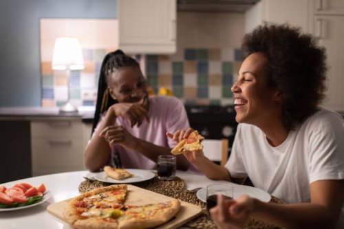 mixed race woman laughing at joke near friend - junk food stock pictures, royalty-free photos & images