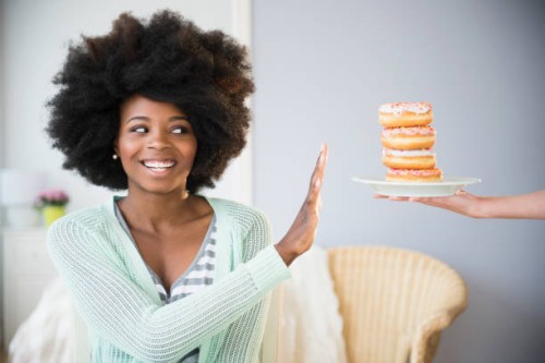 mixed race woman refusing donuts - junk food stock pictures, royalty-free photos & images