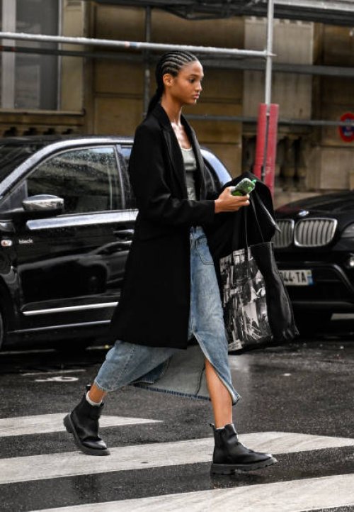 Model is seen wearing a black coat, white top, blue denim slit skirt and black boots outside the Giambattista Valli show during Womenswear...
