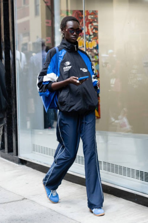 Model is seen wearing a blue and black jacket, blue pant, blue sneakers and brown sunglasses outside the Carolina Herrera show during New York...