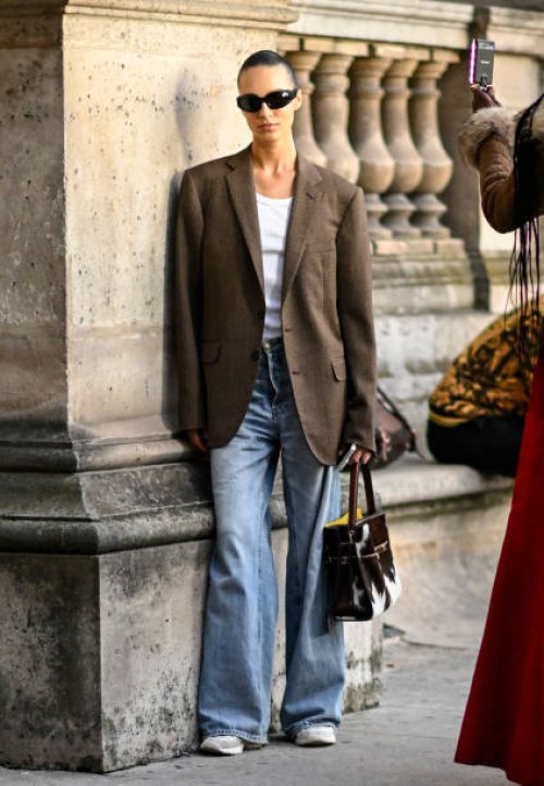 Model is seen wearing a brown blazer and white top, blue jeans cow print bag and black sunglasses outside the Louis Vuitton show during Womenswear...