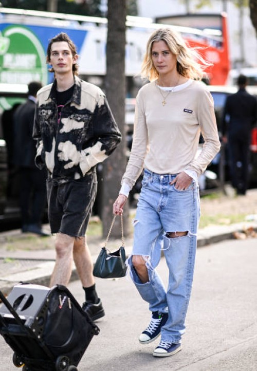 Model is seen wearing a cream Miu Miu shirt, ripped jeans and Prada bag outside the Miu Miu show during the Womenswear Spring/Summer 2024 as part of...