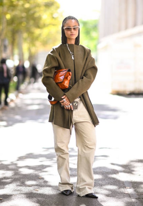Model is seen wearing a green coat, green sweater, tan pants and brown bag outside the Miu Miu show during Womenswear Spring/Summer 2025 as part of...