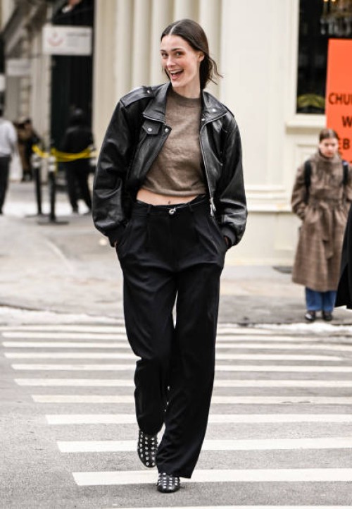 Model Jace Higgins is seen wearing a black leather jacket, tan sweater, black pants and black studded shoes and black bag outside the Kallmeyer show...