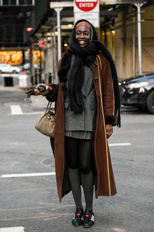 Model Lily Fofana is seen wearing a brown coat, gray sports jacket, gray skirt, gray knee high socks and Adidas sneakers outside the Bronx and Banco...
