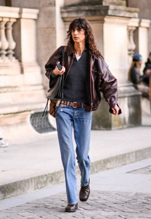 Model Mica Arganaraz is seen wearing a brown leather jacket, black sweater, blue jeans, brown belt and black bag outside the Louis Vuitton show...