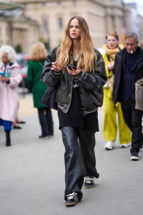 Model wears a black leather bomber jacket , black leather flared pants , Adidas sneakers shoes , outside Chanel, during the Womenswear Fall/Winter...