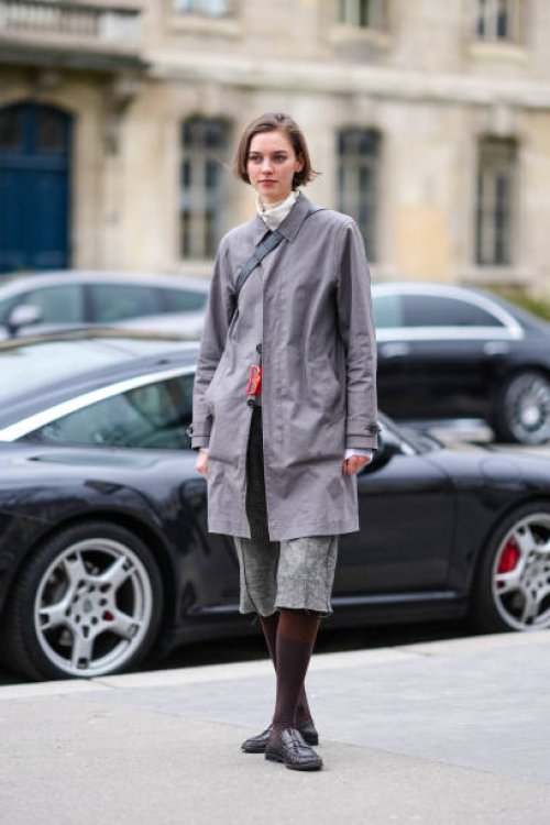 Model wears a gray long coat, shorts, tights, black leather loafers shoes, outside Chanel, during the Womenswear Fall/Winter 2024/2025 as part of...