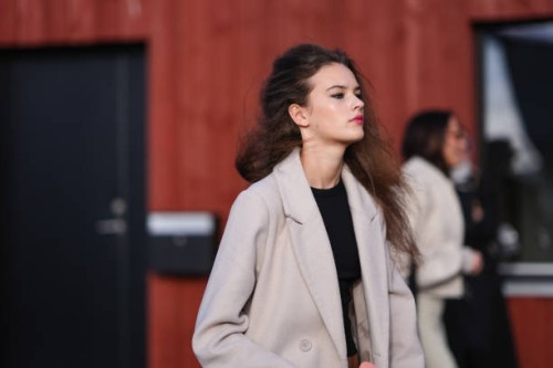 Model wears a white long coat , a black cropped top, red lipstick , make-up , outside Gestuz, during the Copenhagen Fashion Week AW24 on February 01,...