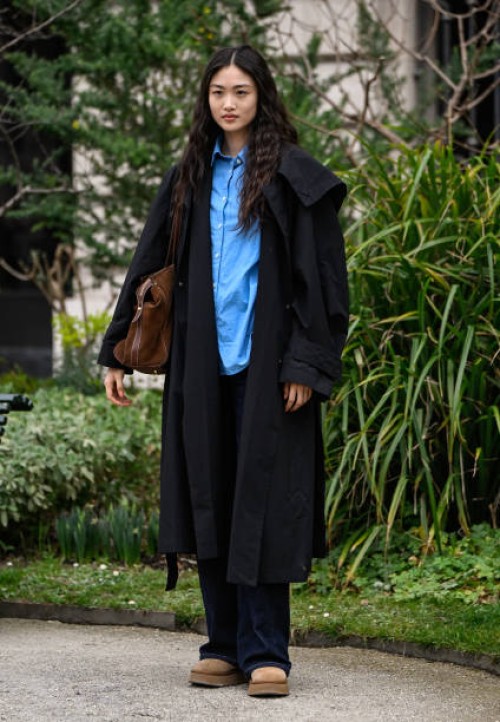 Model Xu Wei is seen wearing a black trench coat, blue shirt, black pants and tan shoes and brown bag outside the Zimmermann show during the...
