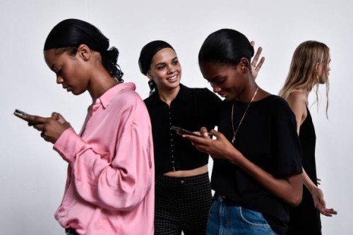 Models check their mobile phone as they wait in the backstage before the Philosophy di Lorenzo Serafini fashion show, as part of the Women's...