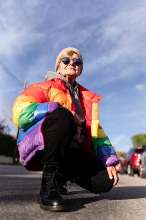 modern grandmother in rainbow coat posing in the middle of the street. - fashion stock pictures, royalty-free photos & images