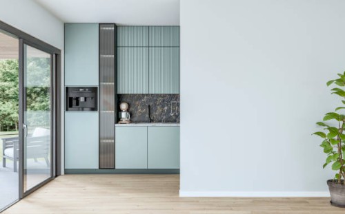 modern powder blue kitchen with large windows (garden view) in the background and a potted plant (ficus) in front of a white blank wall in the foreground - garden decoration stock pictures, royalty-free photos & images
