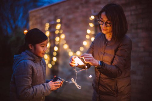 mom & daughter untangling the string lights together while they are decorating the garden at dusk - garden decoration stock pictures, royalty-free photos & images