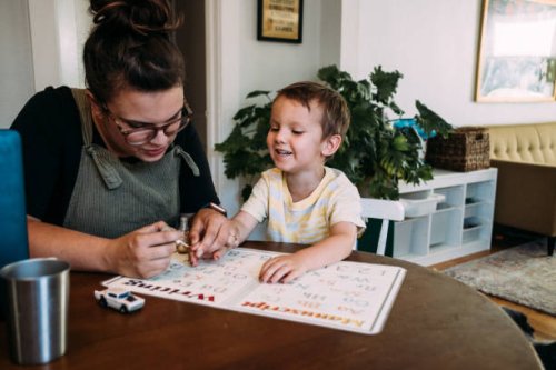 mom painting smiling son's finger nails at kitchen table - nails art photos et images de collection