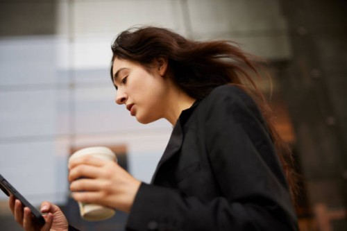 morning rush: woman speeds to work with takeaway coffee and smartphone. - junk food stock pictures, royalty-free photos & images