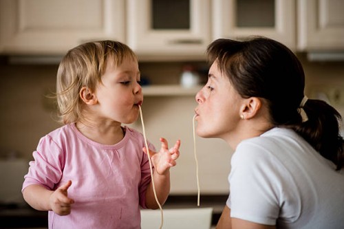 mother and child eating spaghetti together - food stockfoto's en -beelden