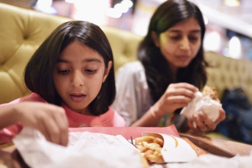 mother and daughter (6-7 years) eating burger and fries - junk food stock pictures, royalty-free photos & images