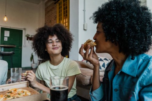 mother and daughter eating pizza in the living room at home - junk food stock pictures, royalty-free photos & images