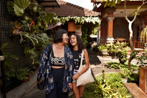 mother and daughter laughing while walking in street market on sunny day - travel stock pictures, royalty-free photos & images
